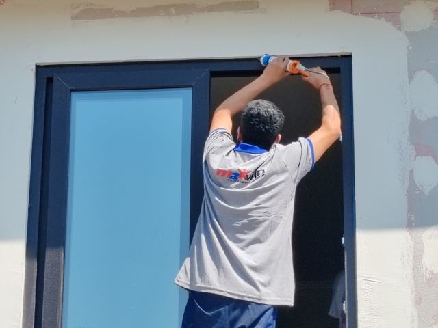 Instalador sellando ventana de PVC antracita