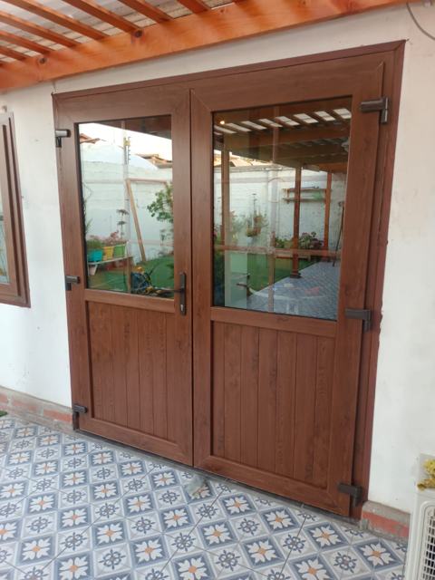 Puerta de PVC de dos hojas color nogal con vidrio hacia el patio