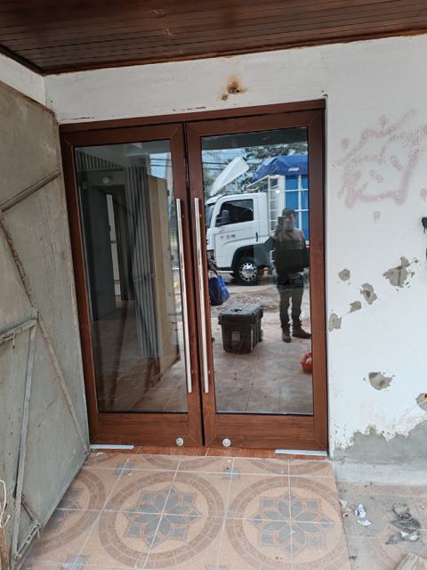 Puerta doble vidriada de PVC color nogal con tirador para local comercial